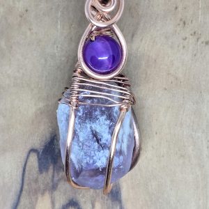 Close up of the Triple Amethyst copper pendant on a wooden display board.